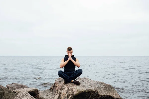 Pria yoga kebugaran yang kuat di Lotus berpose di pantai batu dekat laut. Konsep Harmonik . — Stok Foto
