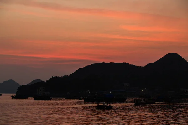 Bateaux de pêche asiatiques au coucher du soleil sur fond de montagnes . — Photo