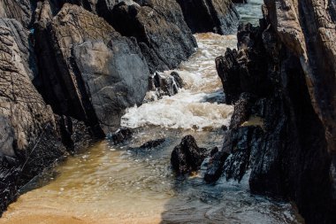 Dalgalar deniz kıyısında, kum plaj isabet