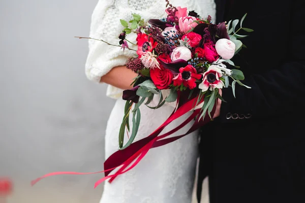 Nevěsta a ženich drží svatební kytici spolu s páskou, mimo Royalty Free Stock Fotografie
