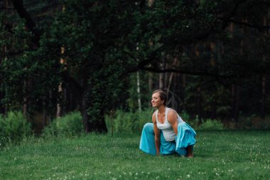 hamile yoga doğum öncesi analık farklı egzersizleri yapıyor. parkta çim, nefes, germe, statik.