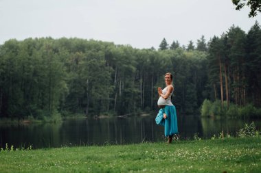 hamile yoga doğum öncesi analık farklı egzersizleri yapıyor. parkta çim, nefes, germe, statik.