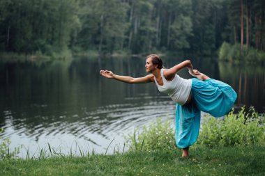 hamile yoga doğum öncesi analık farklı egzersizleri yapıyor. parkta çim, nefes, germe, statik.