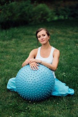 hamile yoga fitball ile farklı egzersizleri yapıyor doğum öncesi. Park çimlerde, nefes, germe, Pilates.