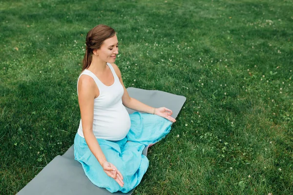 Hamile yoga orman arka plan üzerinde lotus olarak. parkta çim paspas, açık, Sağlık kadın. — Stok fotoğraf