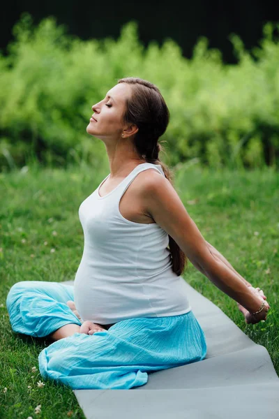 Hamile yoga orman arka plan üzerinde lotus olarak. parkta çim paspas, açık, Sağlık kadın. — Stok fotoğraf