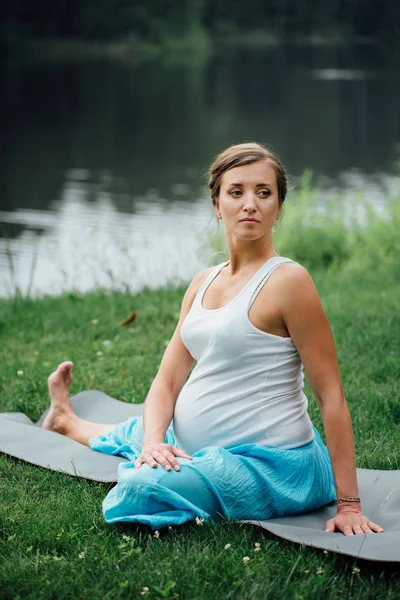 Hamile yoga orman arka plan üzerinde lotus olarak. parkta çim paspas, açık, Sağlık kadın. — Stok fotoğraf