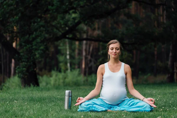 Termos lotus pozisyonla hamile yoga. parkta çim, açık, kadın sağlık, erkek. — Stok fotoğraf