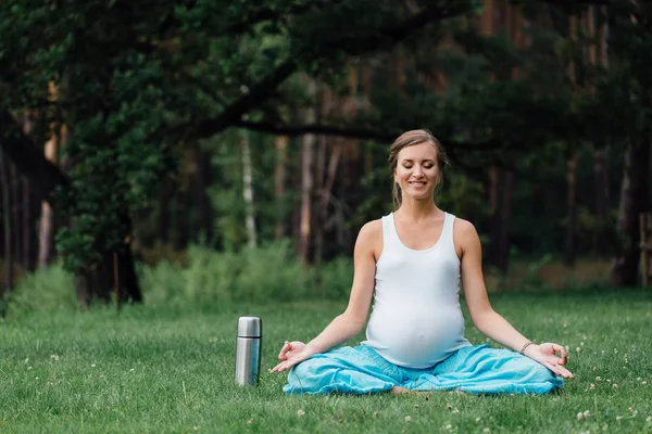 Termos lotus pozisyonla hamile yoga. parkta çim, açık, kadın sağlık, erkek. — Stok fotoğraf