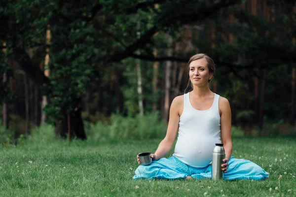 Termos lotus pozisyonla hamile yoga. parkta çim, açık, kadın sağlık, erkek. — Stok fotoğraf