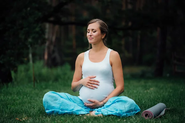 Nefes, germe, statik hamile yoga kadınla çimenlerin üzerinde park mat portre. açık, orman. — Stok fotoğraf