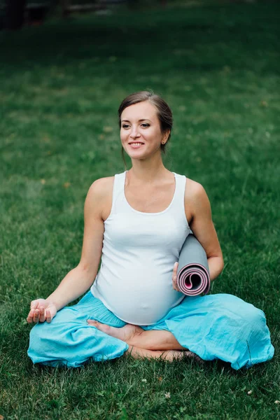 Mujer embarazada de yoga en posición de loto con retrato de esterilla en el parque sobre la hierba, respiración, estiramiento, estática . — Foto de Stock