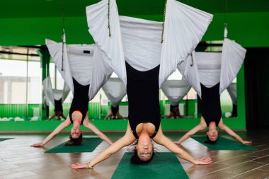 Anti yerçekimi yoga egzersizleri ile bir grup insan yapma genç kadınlar. Aero sinek fitness eğitmeni egzersiz. Beyaz hamak.