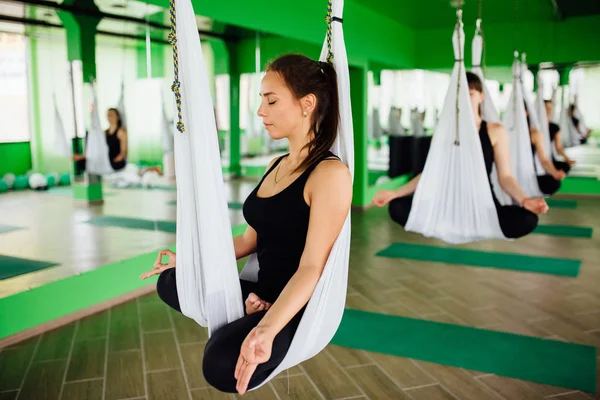 Anti yerçekimi yoga egzersizleri ile bir grup insan yapma genç kadınlar. Aero sinek fitness eğitmeni egzersiz. Beyaz hamak.