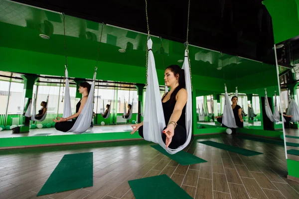 Anti yerçekimi yoga egzersizleri ile bir grup insan yapma genç kadınlar. Aero sinek fitness eğitmeni egzersiz. Beyaz hamak.