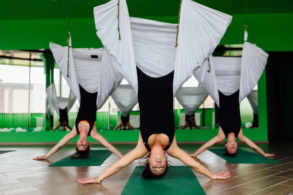 Anti yerçekimi yoga egzersizleri ile bir grup insan yapma genç kadınlar. Aero sinek fitness eğitmeni egzersiz. Beyaz hamak.
