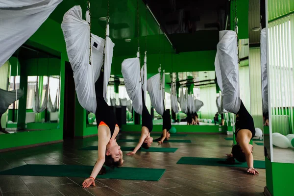 Anti yerçekimi yoga egzersizleri ile bir grup insan yapma genç kadınlar. Aero sinek fitness eğitmeni egzersiz. Beyaz hamak.