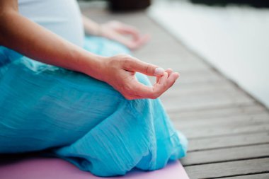 Lotus pozisyonu closeup meditasyon kadın. Yakın çekim mudra eller. Nehir kıyısında ahşap zemin üzerinde oturan