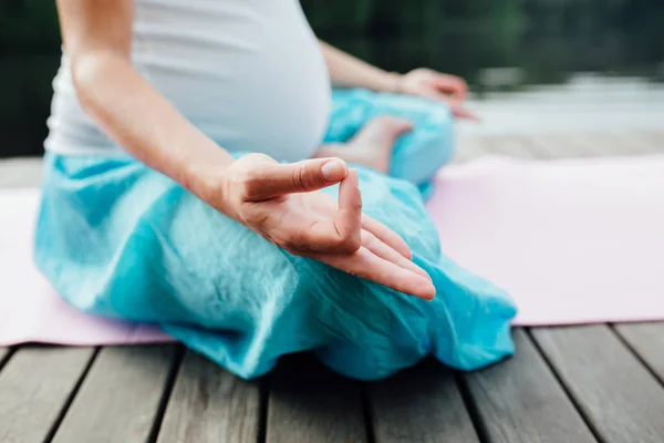 Lotus pozisyonu closeup meditasyon kadın. Yakın çekim mudra eller. Nehir kıyısında ahşap zemin üzerinde oturan — Stok fotoğraf