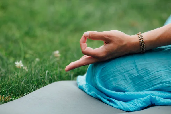 Lotus pozisyonu closeup meditasyon kadın. Yakın çekim mudra eller. Yeşil çim arka plan çim halı üzerinde oturan — Stok fotoğraf