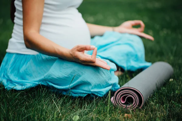 Nefes, germe, statik hamile yoga kadınla lotus pozisyonunda Park çimenlerin üzerinde mat portre. — Stok fotoğraf