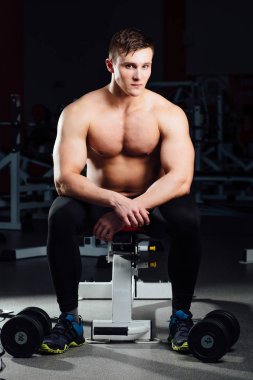 profesyonel vücut geliştirmeci egzersizleri dumbbells vasıl jimnastik salonu ile arasında dinlenme bankta oturmuş. Büyük