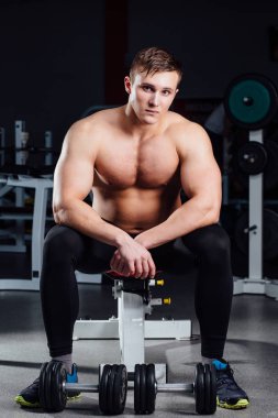 profesyonel vücut geliştirmeci egzersizleri dumbbells vasıl jimnastik salonu ile arasında dinlenme bankta oturmuş. Büyük