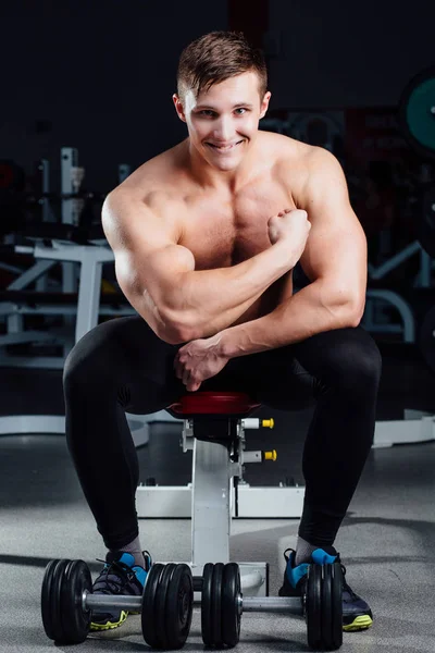 专业的健身健美运动员坐在板凳上和演示你的身体的肌肉锻炼后，在健身房. — 图库照片