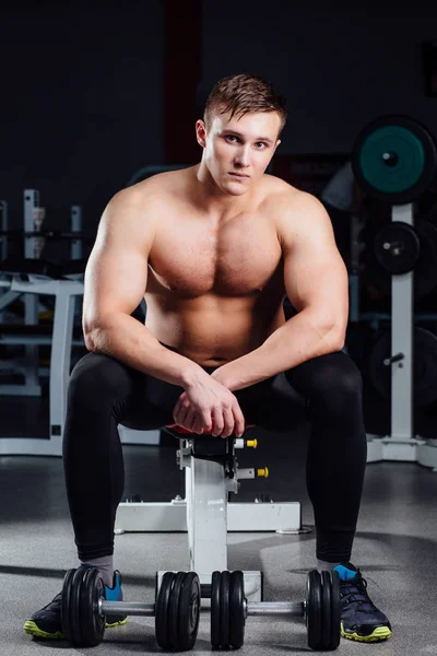 Bodybuilder professionnel assis sur le banc, reposant entre les exercices avec haltères à la salle de gym. Gros ! — Photo