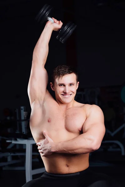 Entraînement bodybuilder professionnel avec haltère assis sur le banc à la salle de gym. Grand entraînement d'homme musclé confiant . — Photo