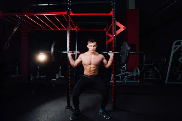 Portrait of a handsome athlete at gym. man does the exercise with  barbell, standing and squatting. big confident — Stock Photo, Image