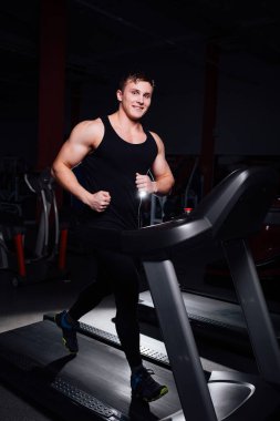 Su şişesi ile koşu bandı üzerinde çalışan spor salonunda genç güçlü büyük adam fitness modeli.