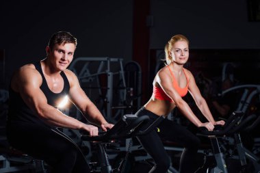 Sportif kaç egzersiz bisikleti üzerinde karanlık bir spor salonu fitness egzersiz.