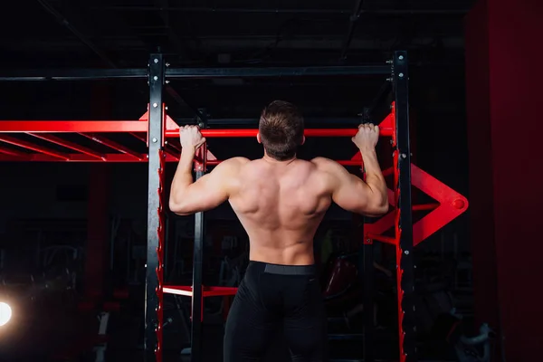 Homme fort faisant pull ups bel athlète à la salle de gym. grand entraînement musculaire confiant . — Photo