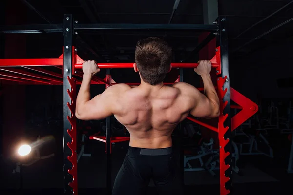 Homme fort faisant pull ups bel athlète à la salle de gym. grand entraînement musculaire confiant . — Photo