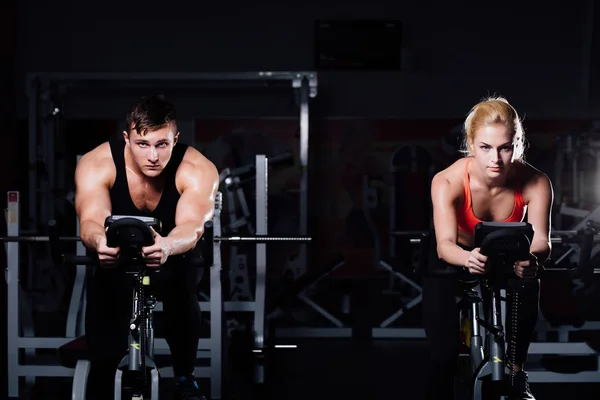Sportif kaç egzersiz bisikleti üzerinde karanlık bir spor salonu fitness egzersiz.