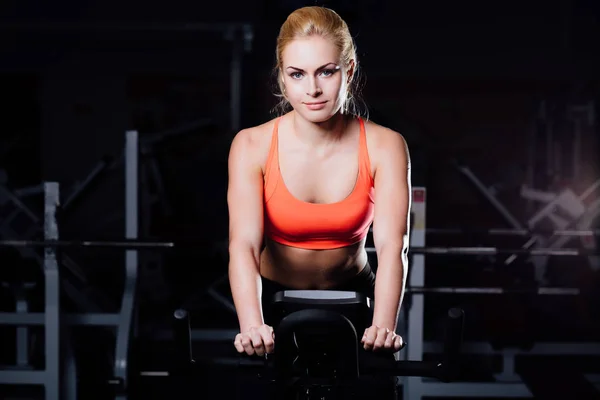 Portret ładny miłego treningu kobiet na fitness rower treningowy ciemny siłowni. — Zdjęcie stockowe