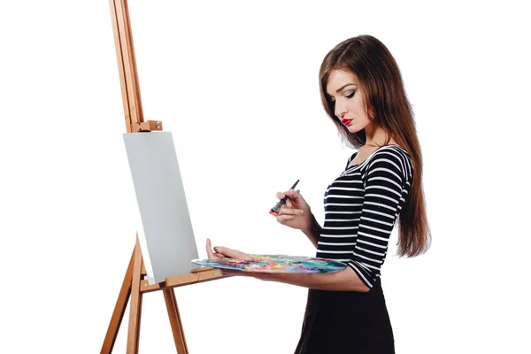 Linda artista hermosa chica pintando un cuadro en caballete de lona. Espacio para el texto. Estudio fondo blanco, aislado . — Foto de Stock