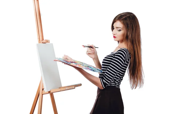 Cute beautiful girl artist painting a picture on  canvas  easel. Space for text. Studio white background, isolated. — Stock Photo, Image