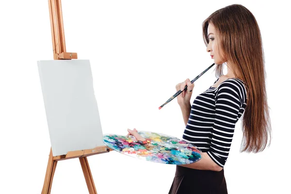 Bonito artista bonito da menina pintando um quadro sobre cavalete de lona. Espaço para SMS. Estúdio fundo branco, isolado . — Fotografia de Stock