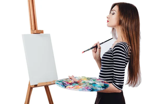 Bonito artista bonito da menina pintando um quadro sobre cavalete de lona. Espaço para SMS. Estúdio fundo branco, isolado . — Fotografia de Stock