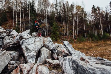 cliff, taşlara oturan resim sanatçı kız not defteri. Harika sonbahar görünümü