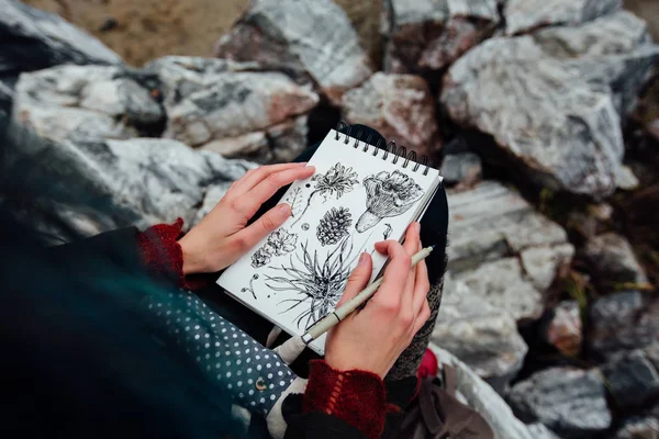 Artista chica pintura sentado en las rocas en el acantilado, bloc de notas. Maravillosa vista otoño — Foto de Stock