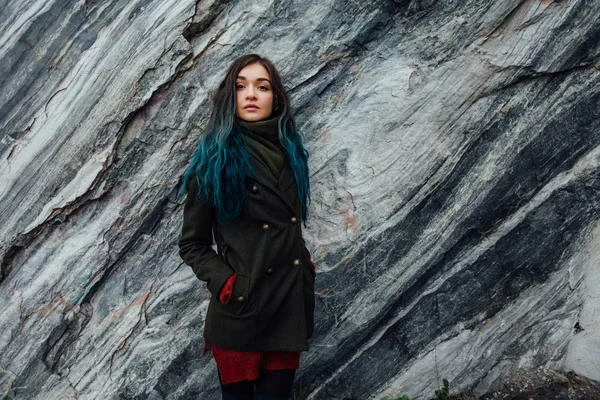 Retrato de una hermosa chica hipster en el fondo los acantilados rocosos. Pelo teñido, azul, largo . — Foto de Stock