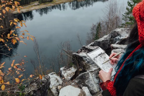 艺术家画坐在悬崖上，岩石上的女孩记事本。美好的秋天视图 — 图库照片