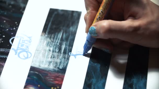 Chica artista firma algunas de sus obras. Signo pintado de un maestro. Impresión de la firma en un rotulador de fieltro azul — Vídeos de Stock