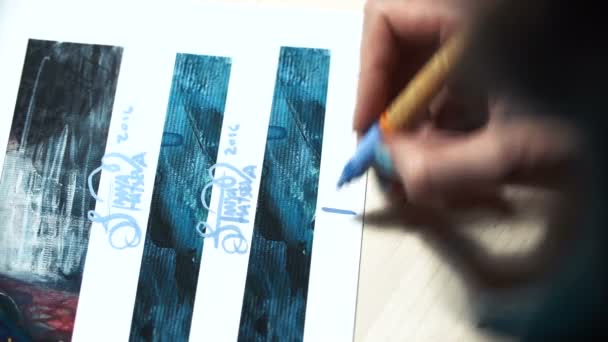 Chica artista firma algunas de sus obras. Signo pintado de un maestro. Impresión de la firma en un rotulador de fieltro azul — Vídeo de stock