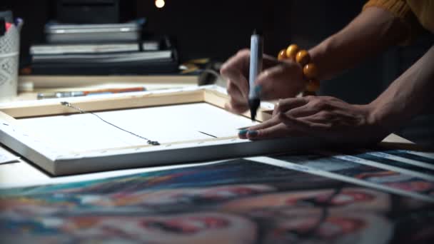 Meisje kunstenaar signeert enkele van zijn werken. Geschilderde teken van een meester. Doek op een brancard handtekening zwarte marker. — Stockvideo