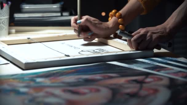 Meisje kunstenaar signeert enkele van zijn werken. Geschilderde teken van een meester. Doek op een brancard handtekening zwarte marker. — Stockvideo