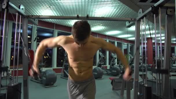 Beau gars athlétique faisant pectoraux sur l'entraîneur crossover dans la salle de gym. vue de face . — Video